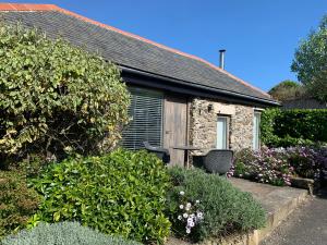 a stone house with a table and chairs in a garden at Lavender Barn in Newquay