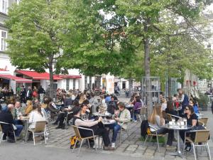 un grupo de personas sentadas en mesas en una calle en GOOD(wo)MAN'S HOME I, en Viena