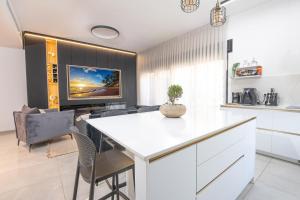 a kitchen and living room with a table and a tv at אחוזת אבישג - וילה יוקרתית עם בריכה מחוממת וממ"ד למשפחות in Shelomi