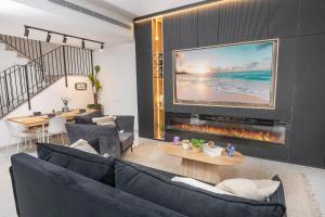 a living room with a large tv and a couch at אחוזת אבישג - וילה יוקרתית עם בריכה מחוממת וממ"ד למשפחות in Shelomi
