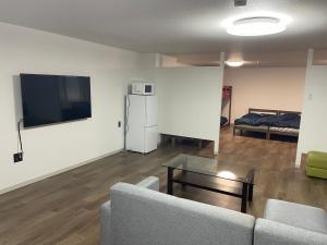 a living room with a couch and a tv on a wall at 民宿一休 in Otaru