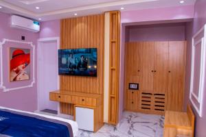 a bedroom with a bed and a tv on a wall at Abiis Hotel and Suites in Abeokuta