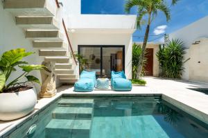 a swimming pool with blue pillows next to a house at Villa Sawahku - 2BR Private Villa with Rooftop & Rice Field View in Canggu +47 photos