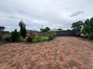 a brick driveway in a yard with a fence at Destiny Executive Apartments in Solwezi +1 photo