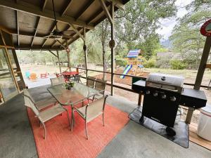 a patio with a table and a grill and a playground at The Cabin at Deer Hollow in Three Rivers