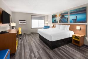 a hotel room with a bed and a flat screen tv at Days Inn by Wyndham Pierre in Pierre +32 photos