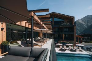 a hotel with a pool with chairs and umbrellas at Grünwald Resort Sölden Appartements und Chalets mit Pool in Sölden