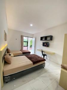 two beds in a room with a desk at Kims Stay Syariah in Jember +17 photos