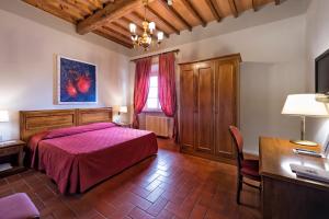 a bedroom with a bed, chair, desk and a lamp at Hotel Miravalle in San Miniato
