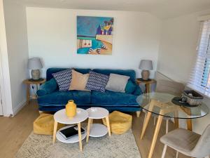 a living room with a blue couch and a glass table at Beach Cottage in Helston