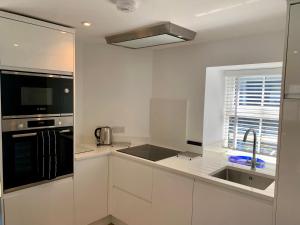 a white kitchen with a sink and a microwave at Beach Cottage in Helston +5 photos