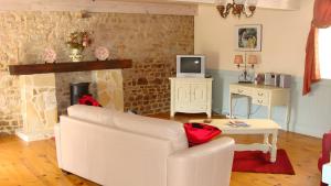 a living room with a white couch and a tv at Grange Cottage - La Mare Chappey in Néhou