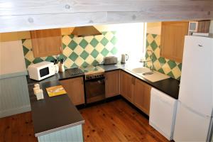 a small kitchen with wooden cabinets and a microwave at Grange Cottage - La Mare Chappey in Néhou