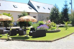 a garden with tables and chairs and umbrellas at Grange Cottage - La Mare Chappey in Néhou +5 photos