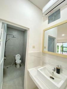 a bathroom with a sink and a toilet and a mirror at Kims Stay Syariah in Jember