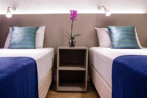 
two beds in a room with a white bedspread at Injoy Lofts Ipanema in Rio de Janeiro
