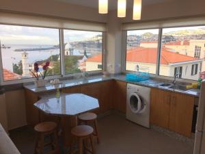 a kitchen with a counter with a table and some windows at Apartamentos Sousa in Funchal