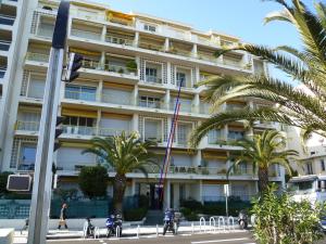 ニースにあるApartment Duplex on Promenade des Anglais 177のヤシの木が目の前に広がる白い建物