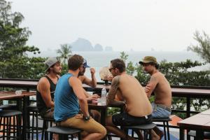 un grupo de hombres sentados en una mesa frente al océano en Balcony Party Hostel - 18-40, en Ao Nang Beach
