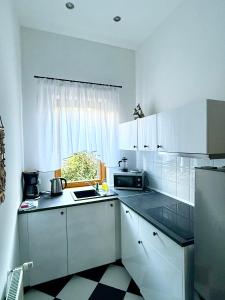 a small kitchen with white cabinets and a window at Willa 4 Pory Roku & Uznam in Świnoujście