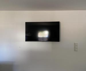 a flat screen tv hanging on a white wall at Hyggehus in Warnitz