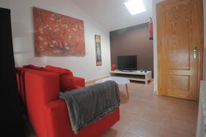 sala de estar con sofá rojo y TV en Cuencaloft La casa de Los Moralejos, en Cuenca