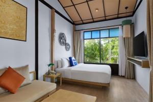 a hotel room with a bed and a window at Homm Chura Samui in Chaweng