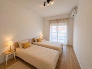 two beds in a white room with a window at Charneca Mar & Sol in Charneca +11 photos