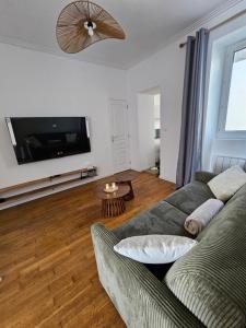 a living room with a couch and a flat screen tv at L'Écrin Manceau Élégance, Sérénité & Confort in Le Mans