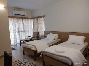 a hotel room with two beds and a chair at KAIBALYA Bliss in Jāmb