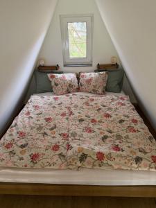a bed with a floral comforter and pillows at Patak Kuckó cabin ház in Szőce