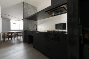 a kitchen with black appliances and a dining table at YOHAKU inuyama in Inuyama