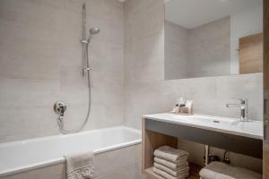 un bagno con vasca, lavandino e doccia di Hotel Mathiesn a Obergurgl