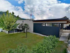 a house with a blue garage and a tree at Gästehaus Marion Appartements in Sankt Peter ob Judenburg