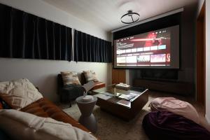 a living room with a couch and a large screen television at The triangle hub Miyazaki in Miyazaki