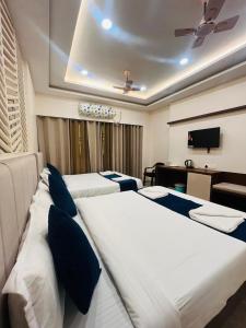 a hotel room with three beds and a television at Maa Prabha Courtyard in Varanasi