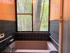 a black tiled bathroom with a window and a sink at BBQ屋根付き大型ウッドデッキ川のせせらぎを聴きながら贅沢時間ペット同伴OK森と音に癒されるコテージ Rill in Nasu