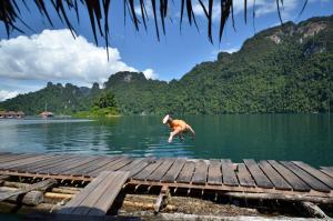 
a man flying through the air over a body of water at Coco Khao Sok Hostel in Khao Sok
