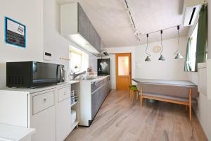 a kitchen with white cabinets and a sink and a table at The triangle hub Miyazaki in Miyazaki