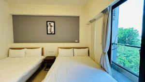 two beds in a room with a window at 日沐澄旅 l 家人聚會 l 烤肉 l 戲水池 l 電動麻將 l KTV l 影音TV in Ch'ih-k'an