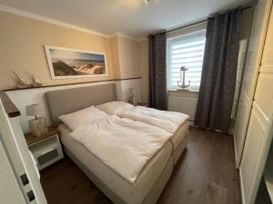 a small bedroom with a bed and a window at Mein Horumersiel in Horumersiel