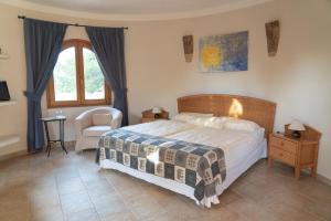 a bedroom with a bed and a chair and a window at Landhotel Can Davero in Binissalem