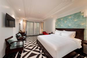 a bedroom with a large white bed and a desk at SaLa Tam Coc Hotel & Spa in Ninh Binh