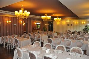 um salão de banquetes com mesas e cadeiras brancas e lustres em Hotel Rainer em Braşov