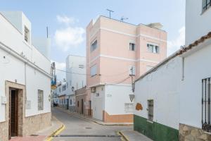a street with white buildings and a pink building at Apartamento Almadraba in Barbate