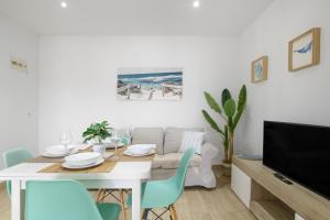 a dining room with a white table and a tv at Apartamento Almadraba in Barbate