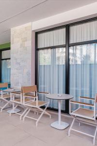 Eine Gruppe von Stühlen und Tischen in einem Raum mit Fenstern in der Unterkunft Mega Hostel in Sarandë