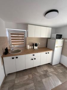 a kitchen with white cabinets and a sink and a refrigerator at Casa TeoMar in Brad