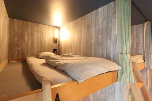 ein Bett in einem Zimmer mit einer Wand in der Unterkunft Re AERU in Minamiboso