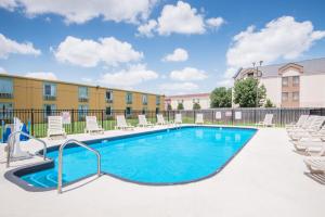 a swimming pool with lounge chairs and a building at Days Inn by Wyndham Joplin in Joplin